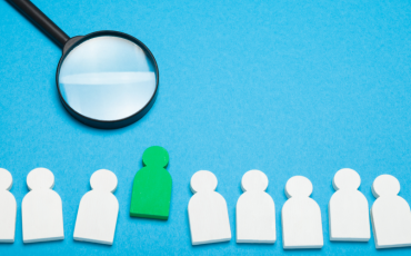 magnifying glass hovering over stand out candidate in a line of figures