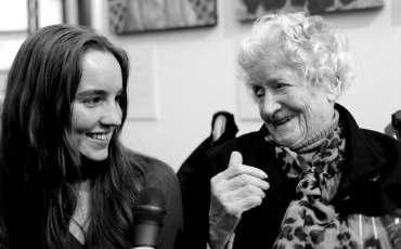 Teenage artist seated next to her centenarian who is the subject of her portrait